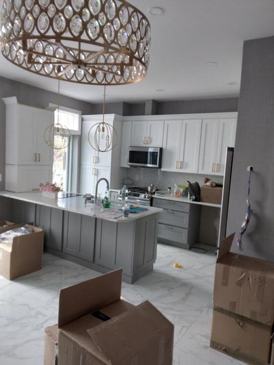Open kitchen with chandelier, two-tone cabinets, and marble-look floor tile