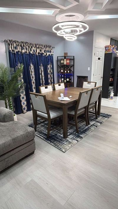 Dining area with light gray plank flooring and coffered ceiling lighting