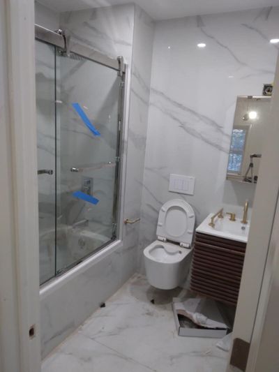 Bathroom with wall-mounted toilet, slatted wood vanity, and glass shower doors