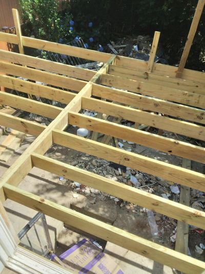 Wood deck joist framing over a backyard base