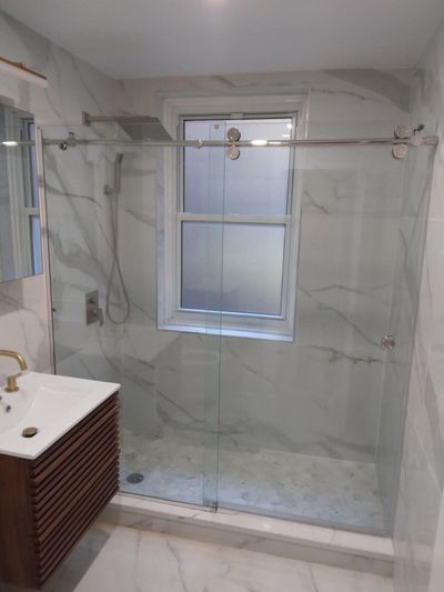 Bathroom with marble-look tile, sliding glass shower door, and slatted wood vanity