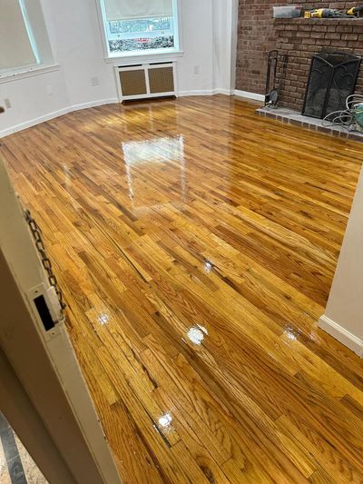 Refinished oak floor beside a red brick fireplace