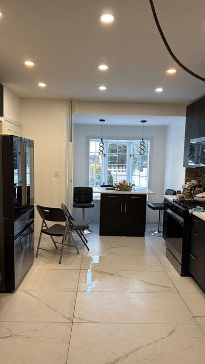 Kitchen with dark cabinets, white marble-look floor tile, and breakfast nook