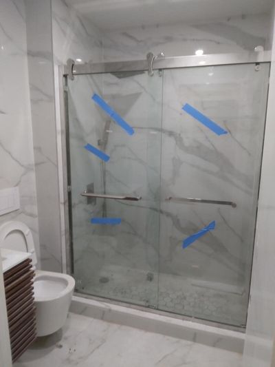 Shower enclosure with marble-look tile and taped sliding glass doors